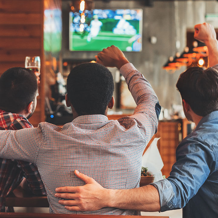 Three men watching football on TV in bar